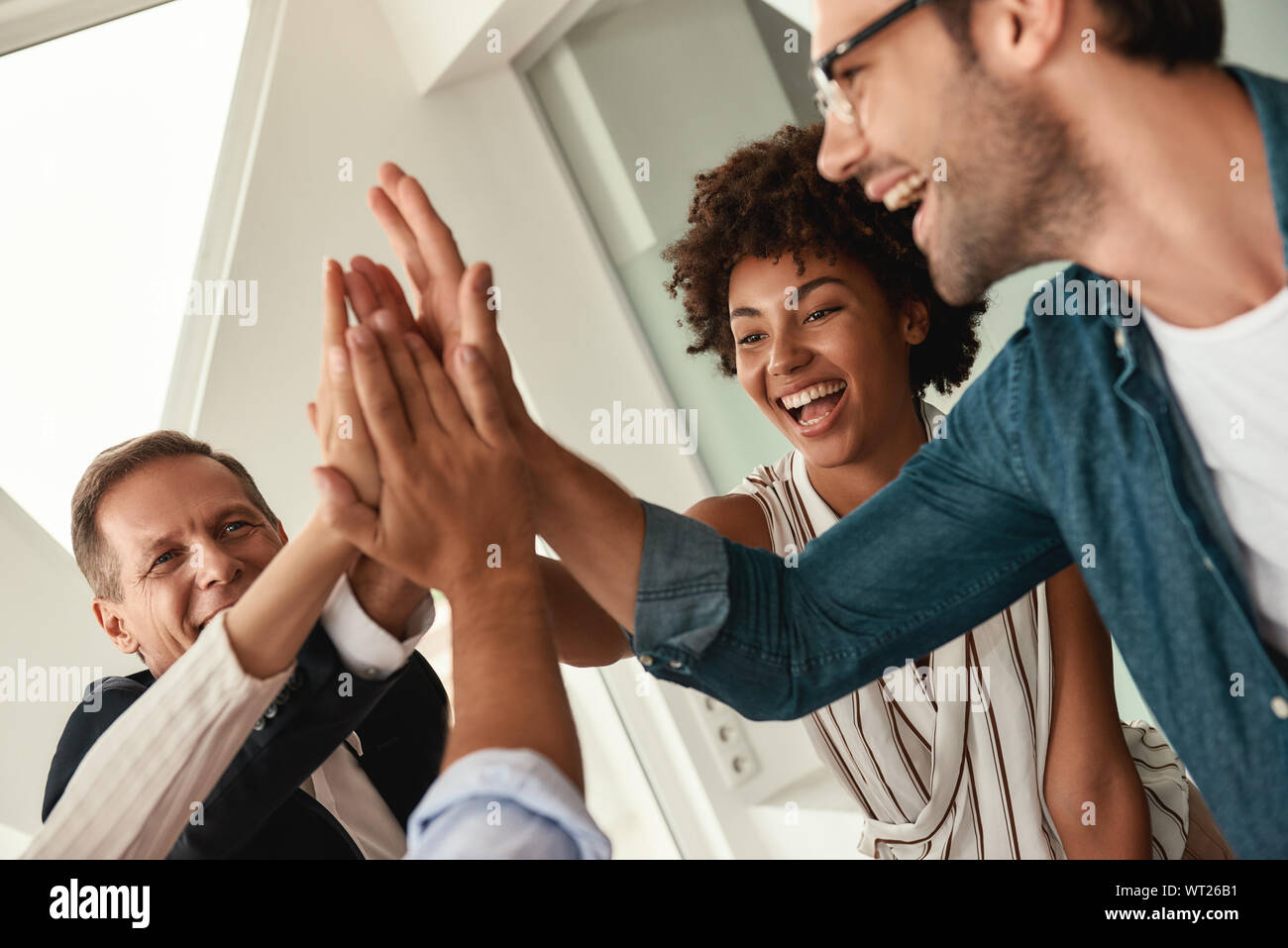 Celebrating success. Business people giving each other high-five and smiling while working together in the modern office. Teamwork Stock Photo