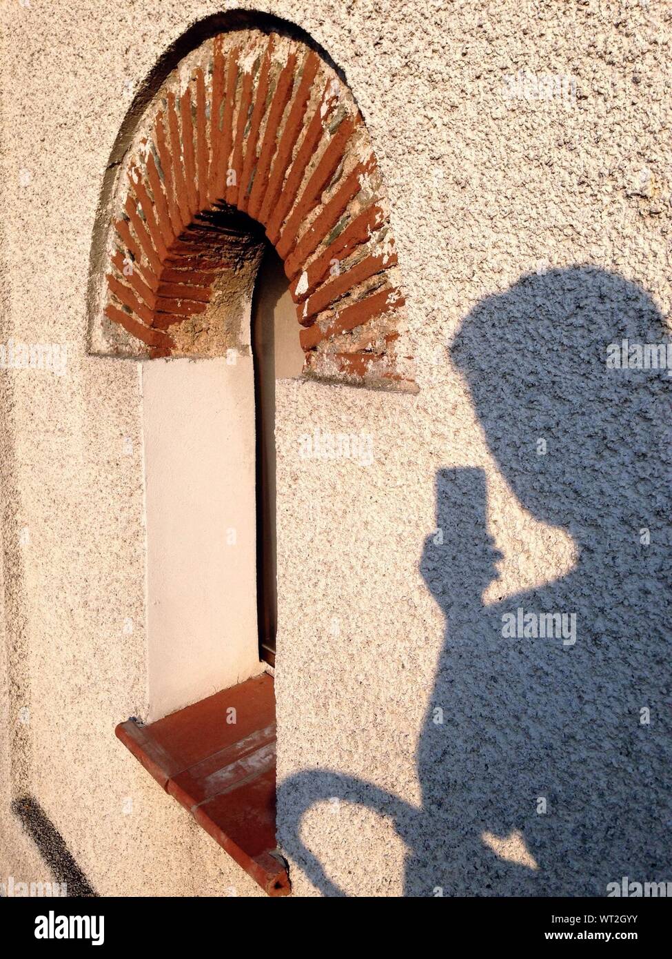 Shadow Of Man With Camera Phone On Wall Stock Photo