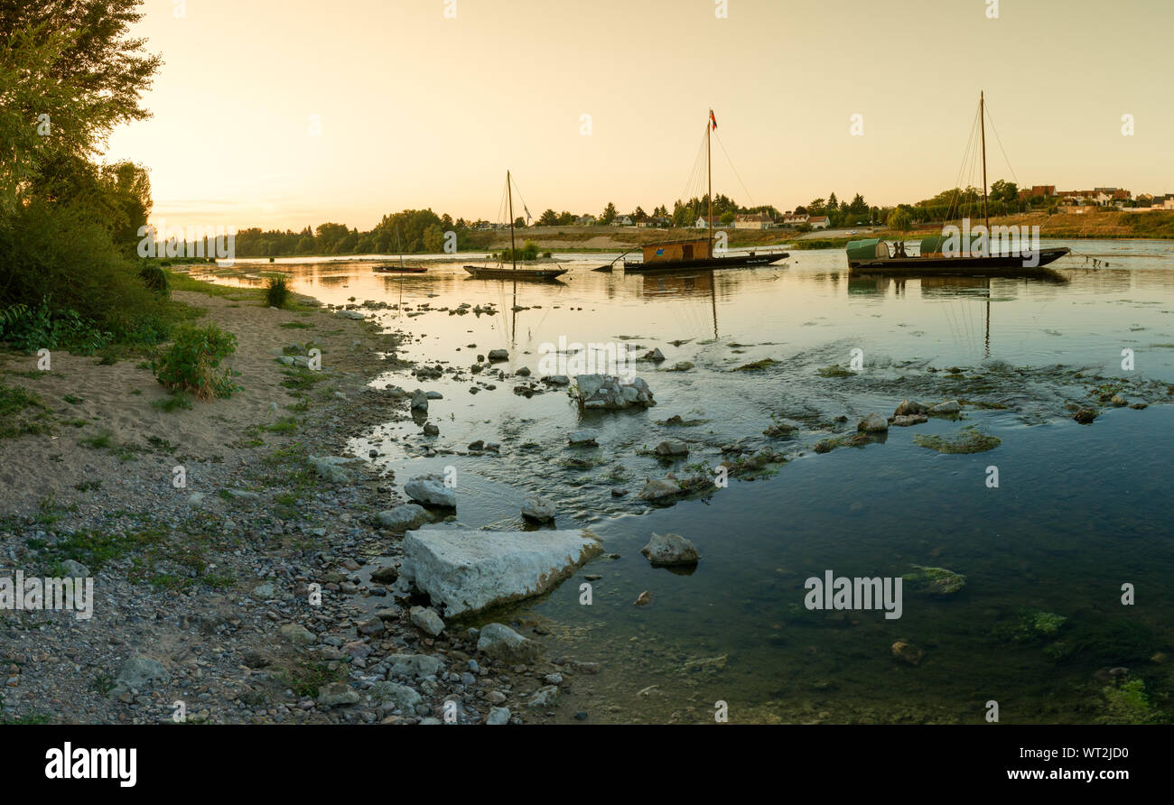 Jargeau, Loire / France - 26 August 2019: wooden riverboats ona calm Loire River at sunset in the French countryside near Orleans Stock Photo