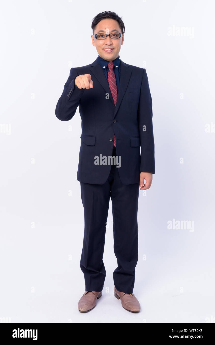 Full body shot of happy Japanese businessman in suit pointing at camera ...