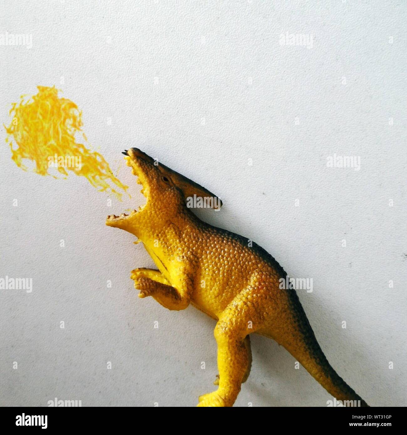 Optical Illusion Of Dinosaur Blowing Fire Against Wall Stock Photo