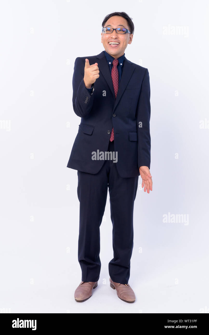 Full body shot of happy Japanese businessman in suit pointing finger ...