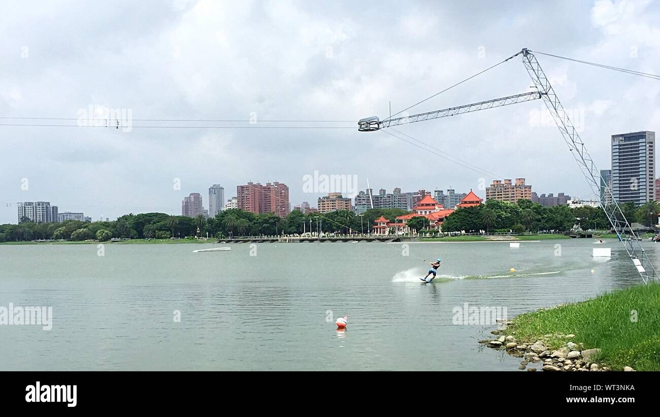 Person Waterski In Lotus Pond Against Cloudy Sky Stock Photo