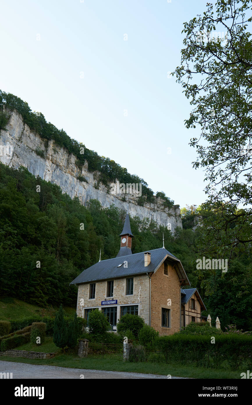 Restaurant des Grottes and the limestone Jura escarpment cliffs in Baume-les-Messieurs Jura France. Stock Photo