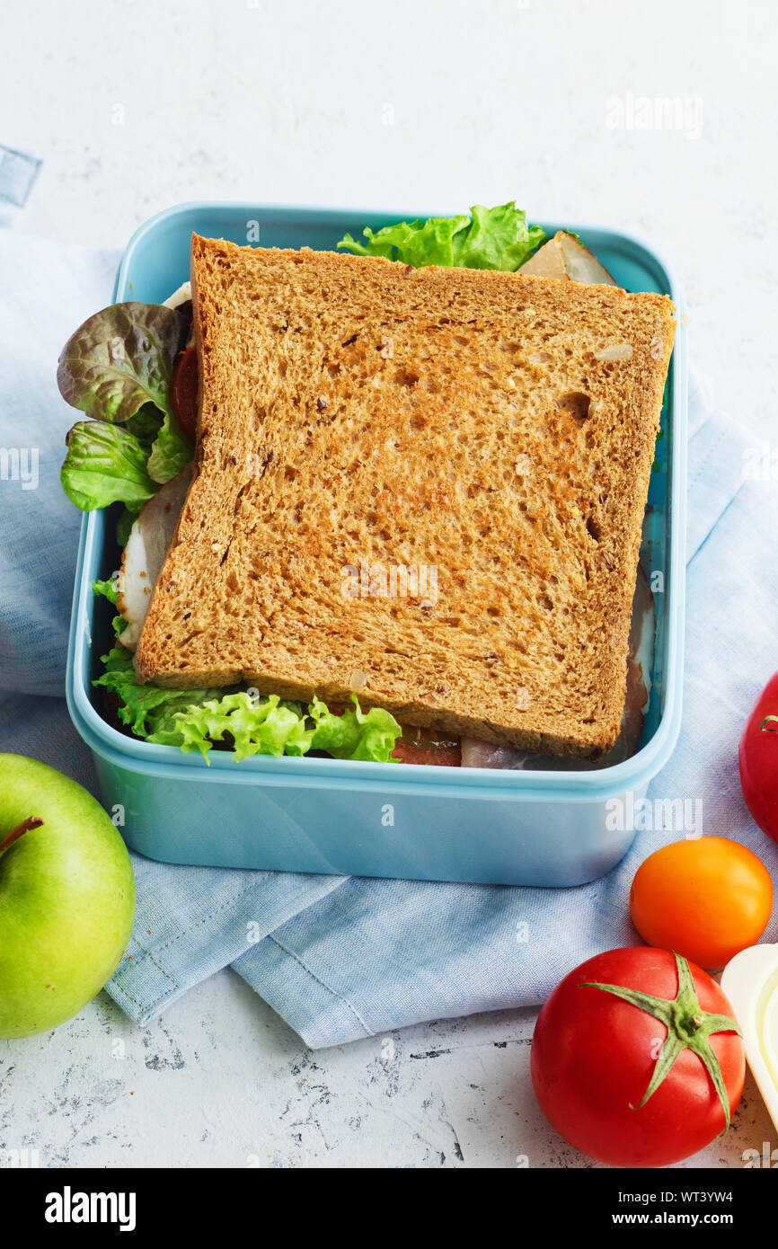 Healthy sandwich with greens, ham, tomatoes and cheese packed in plastic container. Takeaway food for lunch at school or at work. Stock Photo