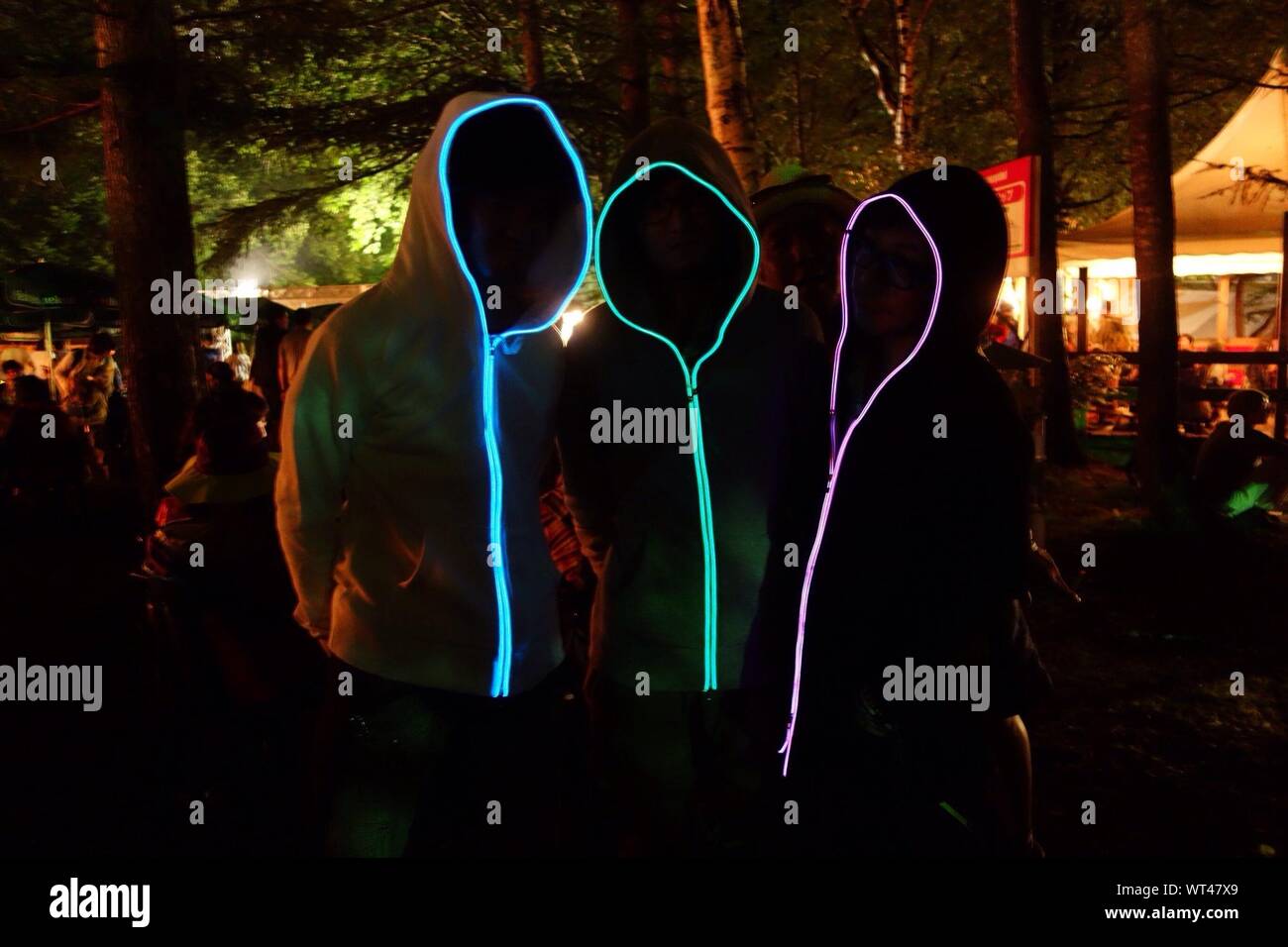 People Wearing Glowing Hooded Sweatshirt At Night Stock Photo