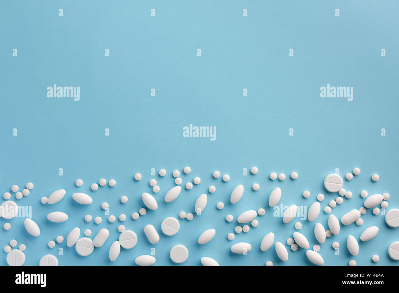 White pills on blue background. Flat lay. Stock Photo