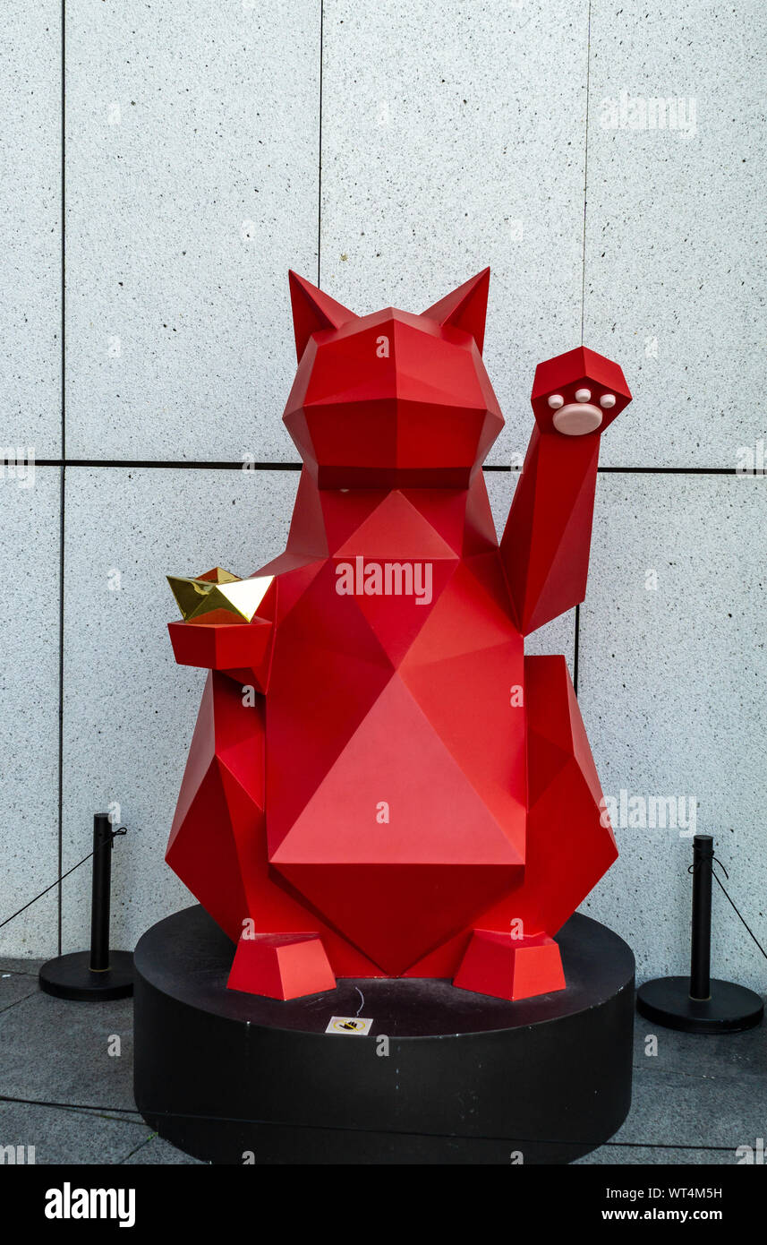 Red maneki-neko fortune cat brings good luck to business owner when placed outside store Stock Photo