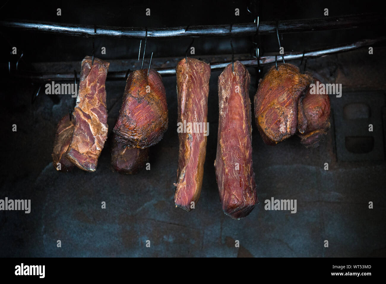 Smoked pork meat in smoker on dark background. Stock Photo