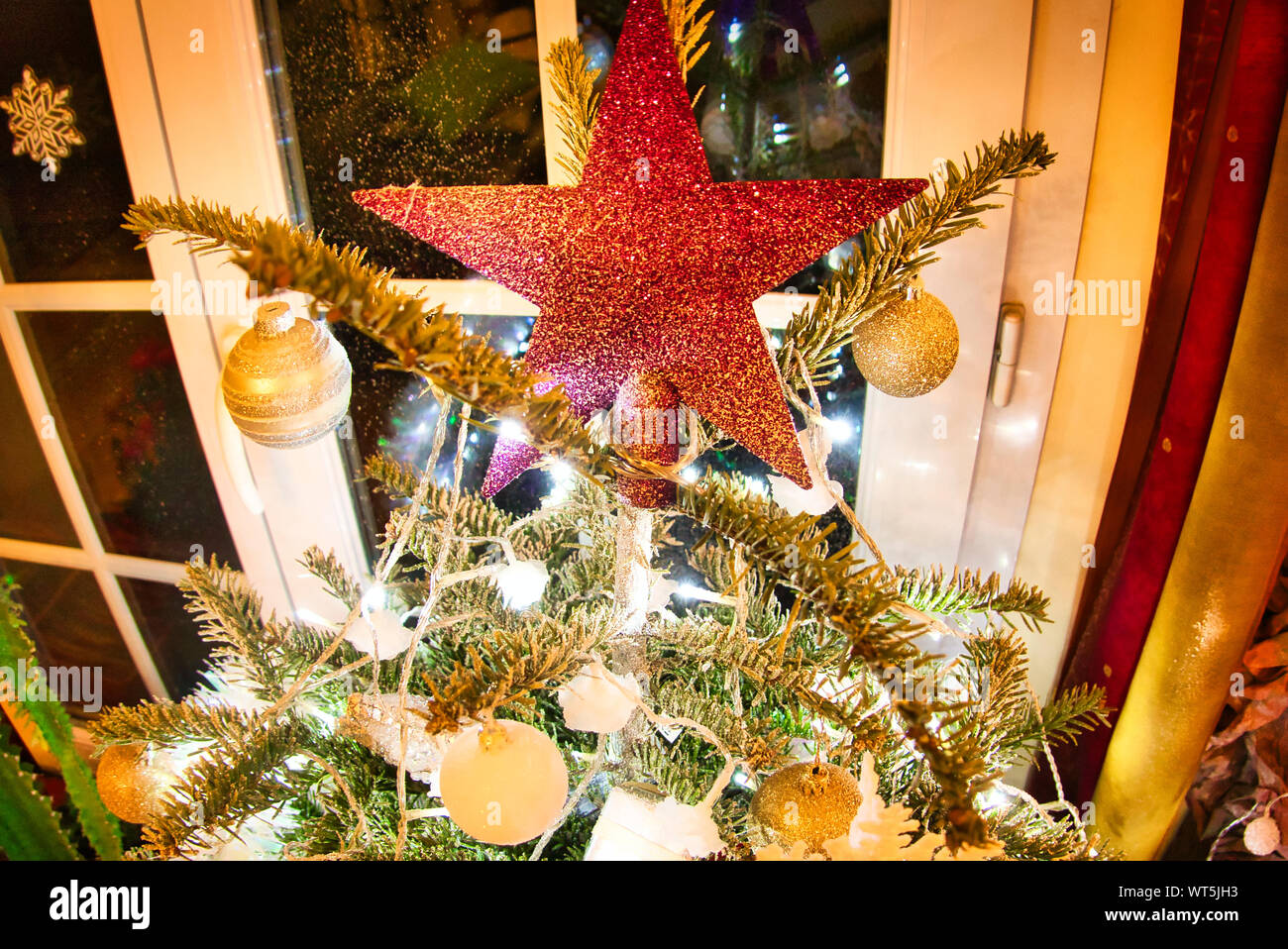 Christmas tree with red shiny star and gold white toys in the interior. Traditional christmas tree in France. Stock Photo