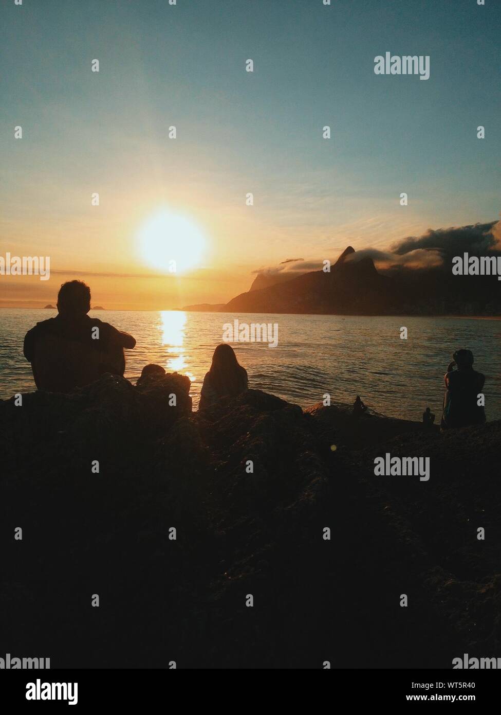 Silhouette People Relaxing At Arpoador Beach During Sunset Stock Photo