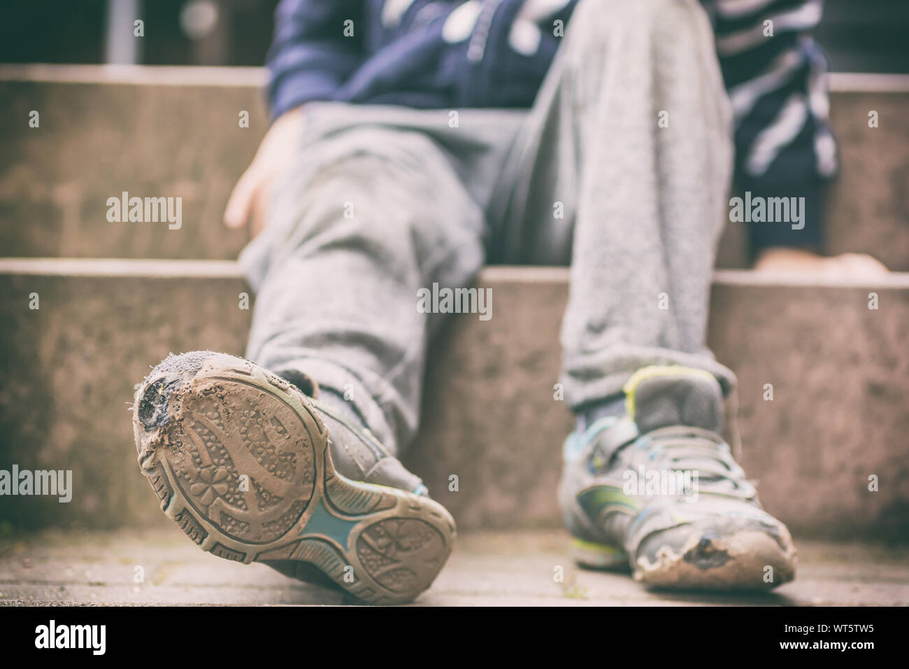 Old broken shoes of a little boy as a symbol for child poverty Stock Photo