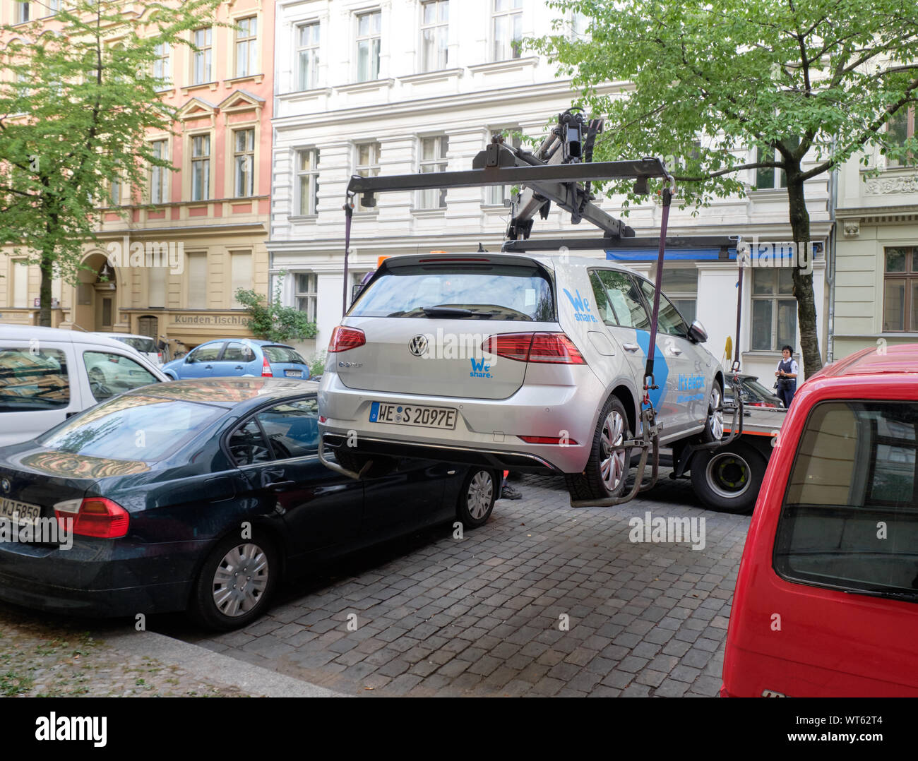 Electric car sharing vehicle being lowered in parking spot by towing
