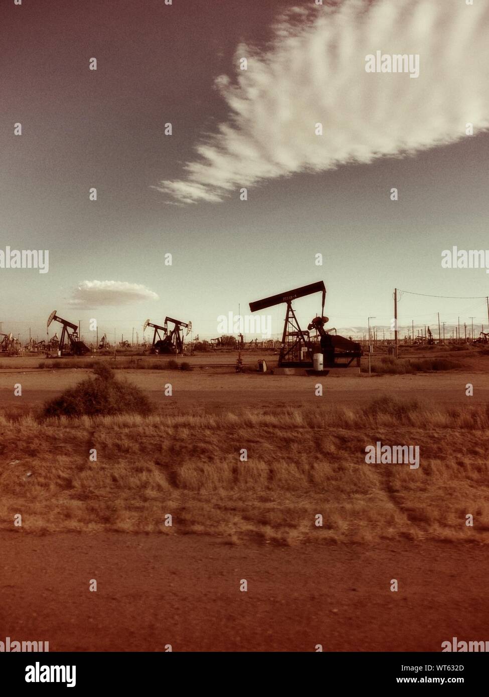 Crude Oil Machinery On Field Against Sky Stock Photo