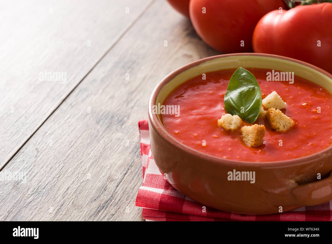 Tomato soup in brown bowl on wooden table. Copy space Stock Photo