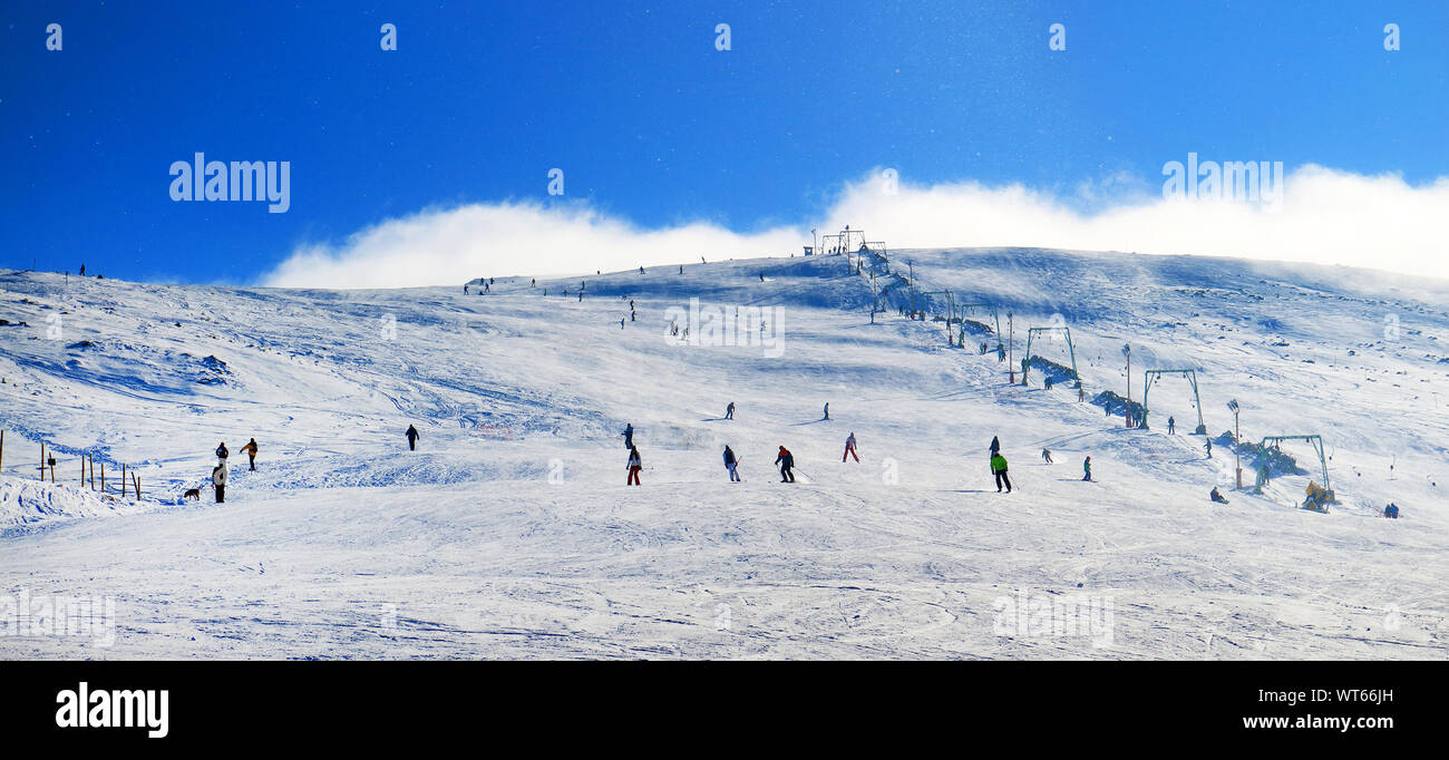 People Skiing Down Snowy Mountain Stock Photo