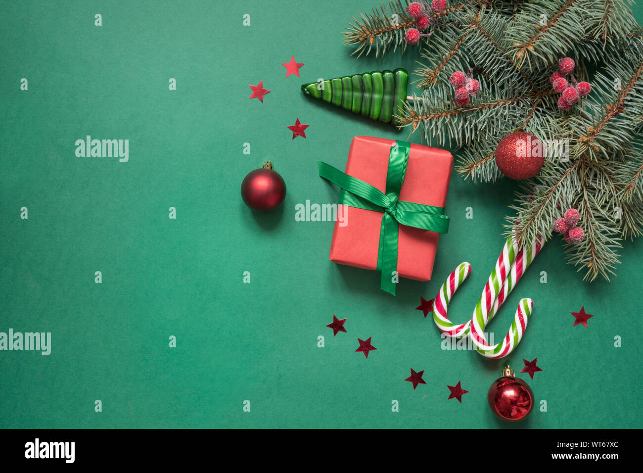 Christmas tree branches, red glass balls and gift box on green with ...