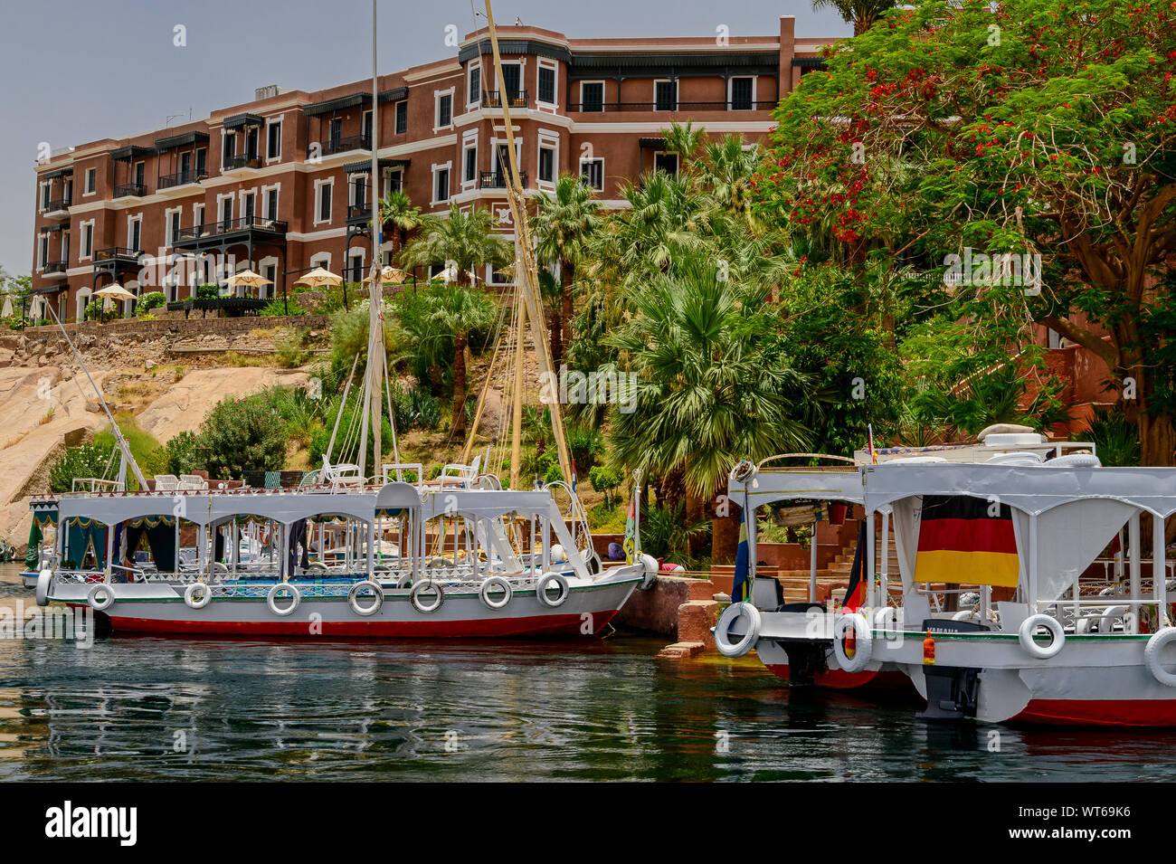 Small passenger ferry boats anchored in front of the historic Old Cataract Hotel in Aswan Stock Photo
