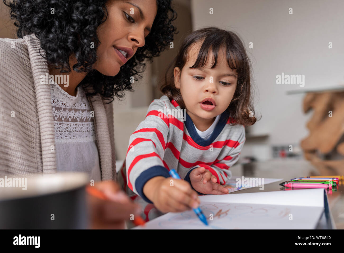 Caring mother and her adorable little girl coloring at home Stock Photo