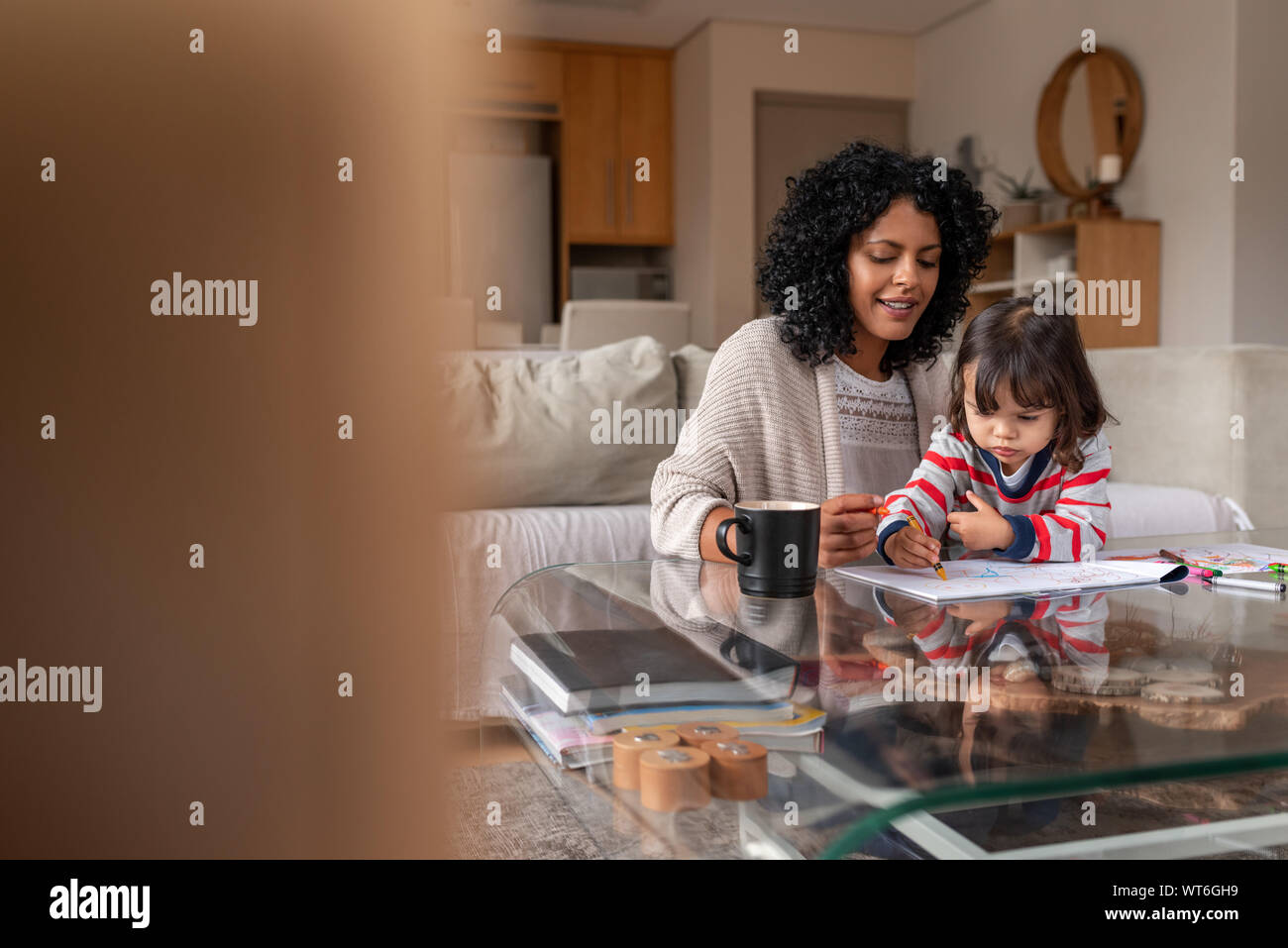 Cute little girl coloring with her loving mother at home Stock Photo ...