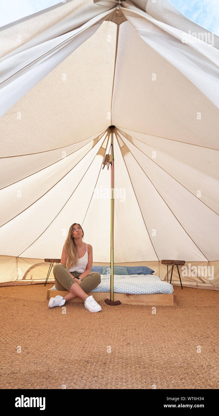 Young woman contemplating the interior of an enormous camping tent Stock Photo