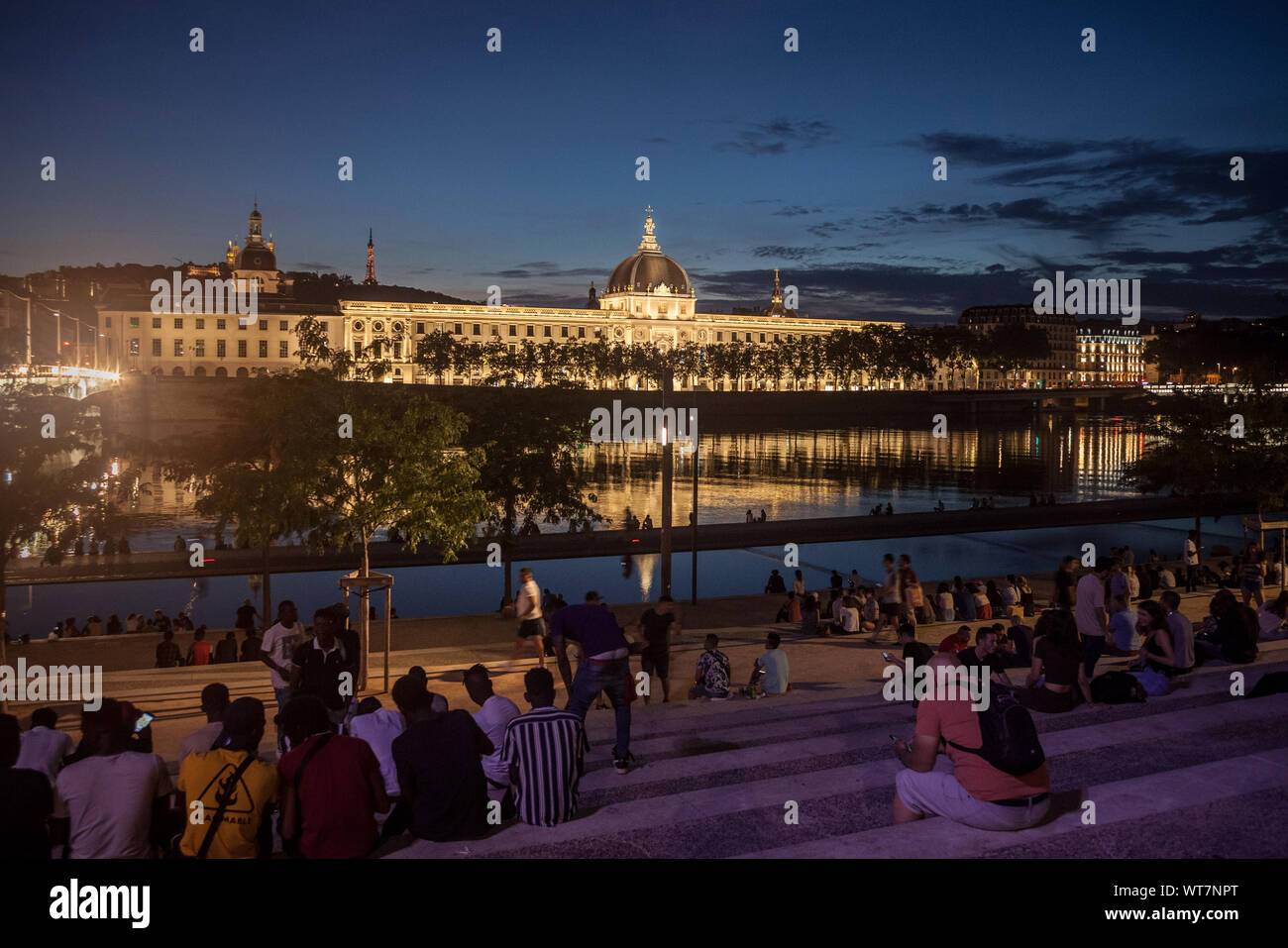 LYON, FRANCE - JULY 18, 2019: French people sitting on the riverbank of ...