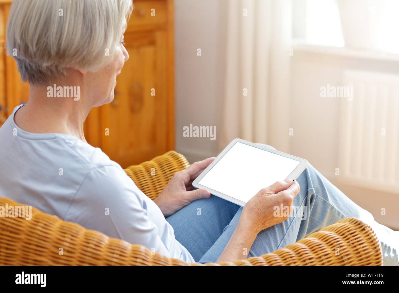 technology and senior people concept, elderly woman with tablet computer in her living room at home Stock Photo