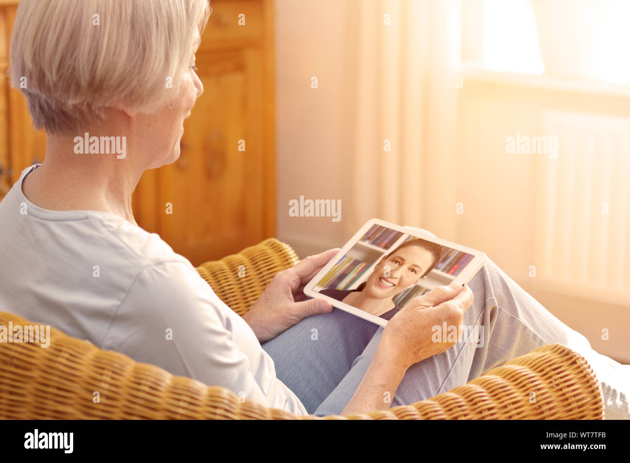 technology and senior people concept, elderly woman with tablet pc viewing family photo album at home Stock Photo