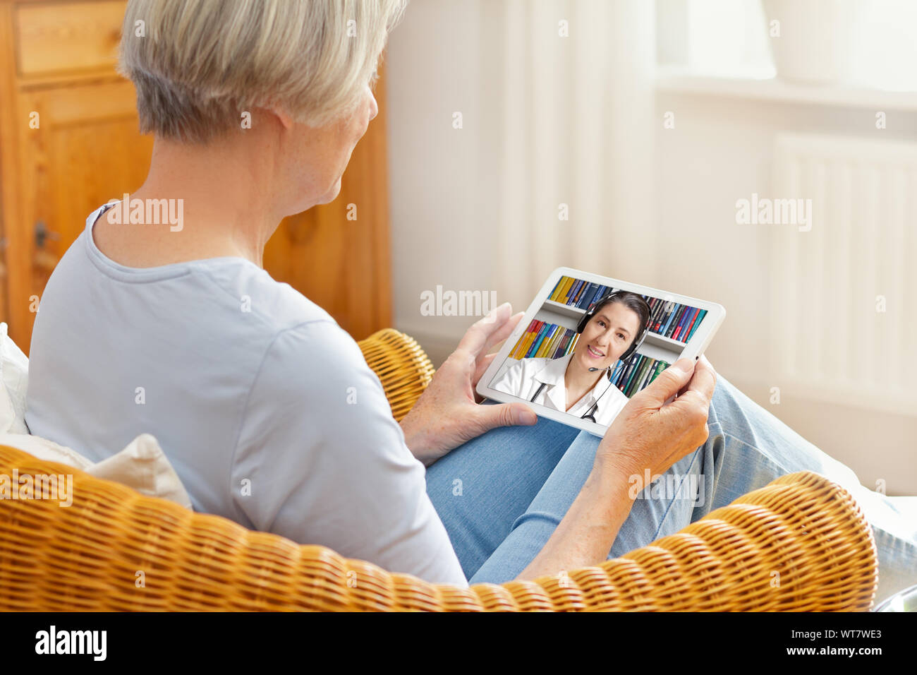 telemedicine concept, old woman with tablet pc during an online consultation with her doctor in her living room Stock Photo