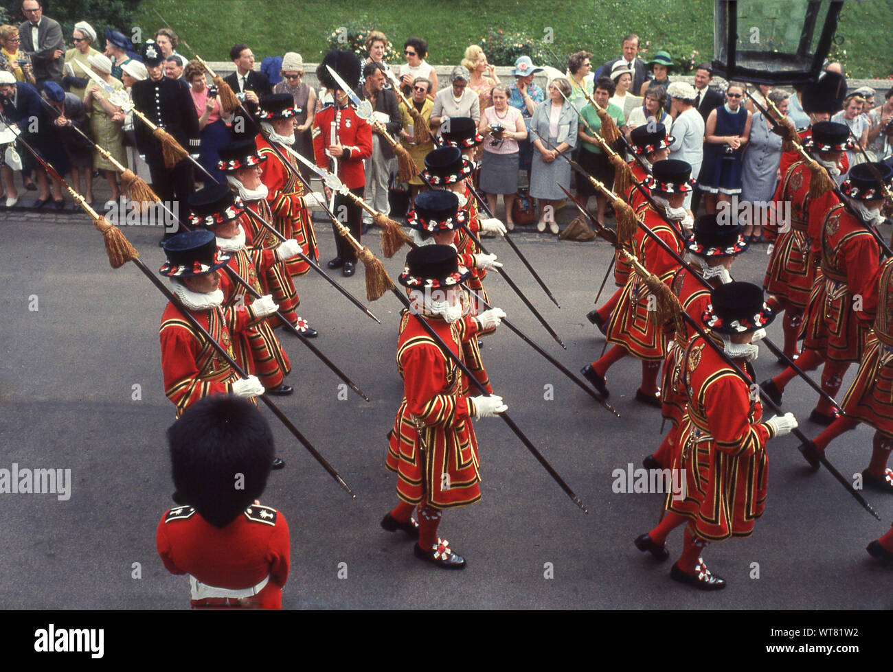 1960s, Windsor, England, UK. Noble Order of the Garter, people watching the procession taking place as Yeoman Guards match outside the castle to Stt George's Chapel for the annual Garter Service. Founded in 1348 it is the oldest British order of Chivalry. Stock Photo