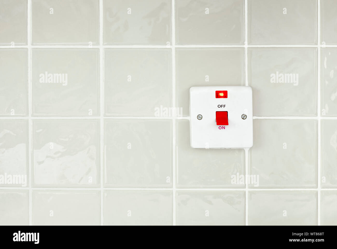 Kitchen appliance on off switch on a glossy tiled wall Stock Photo