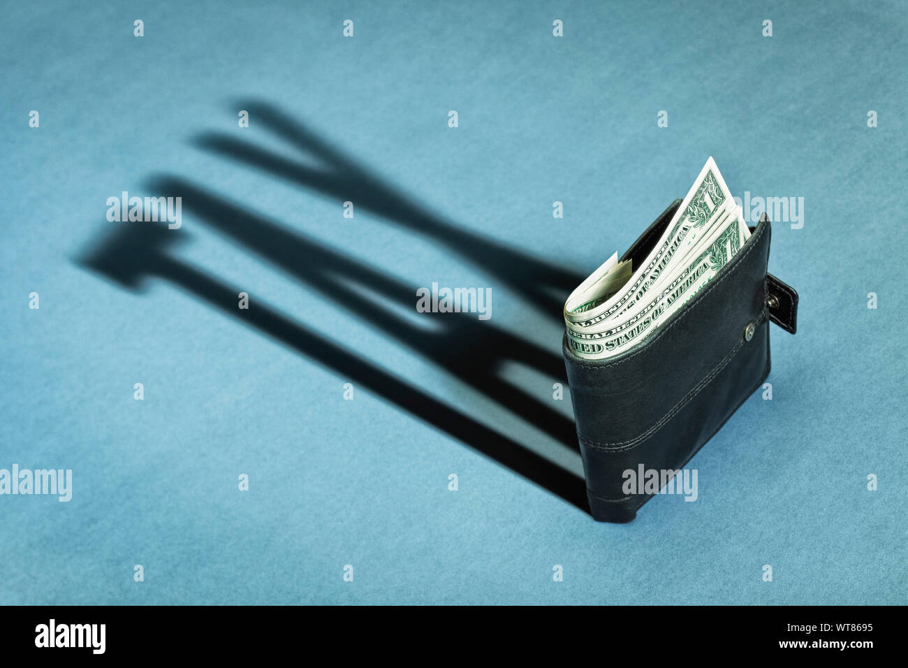 Wallet with US Dollars casting a shadow of tax, taxes or taxation Stock Photo