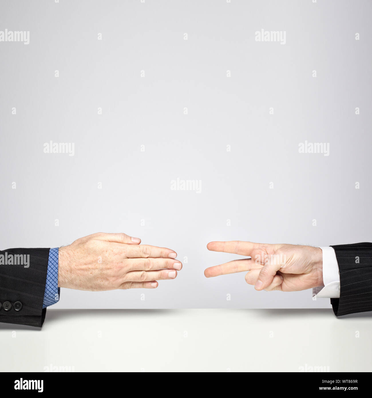Two businessmen playing Rock, Paper, Scissors – Scissors beat Paper Stock Photo