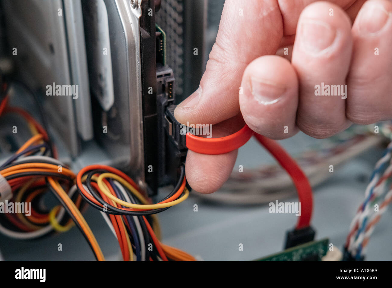 Hand of man plugging SATA (Serial AT Attachment, Serial ATA) data cable ...