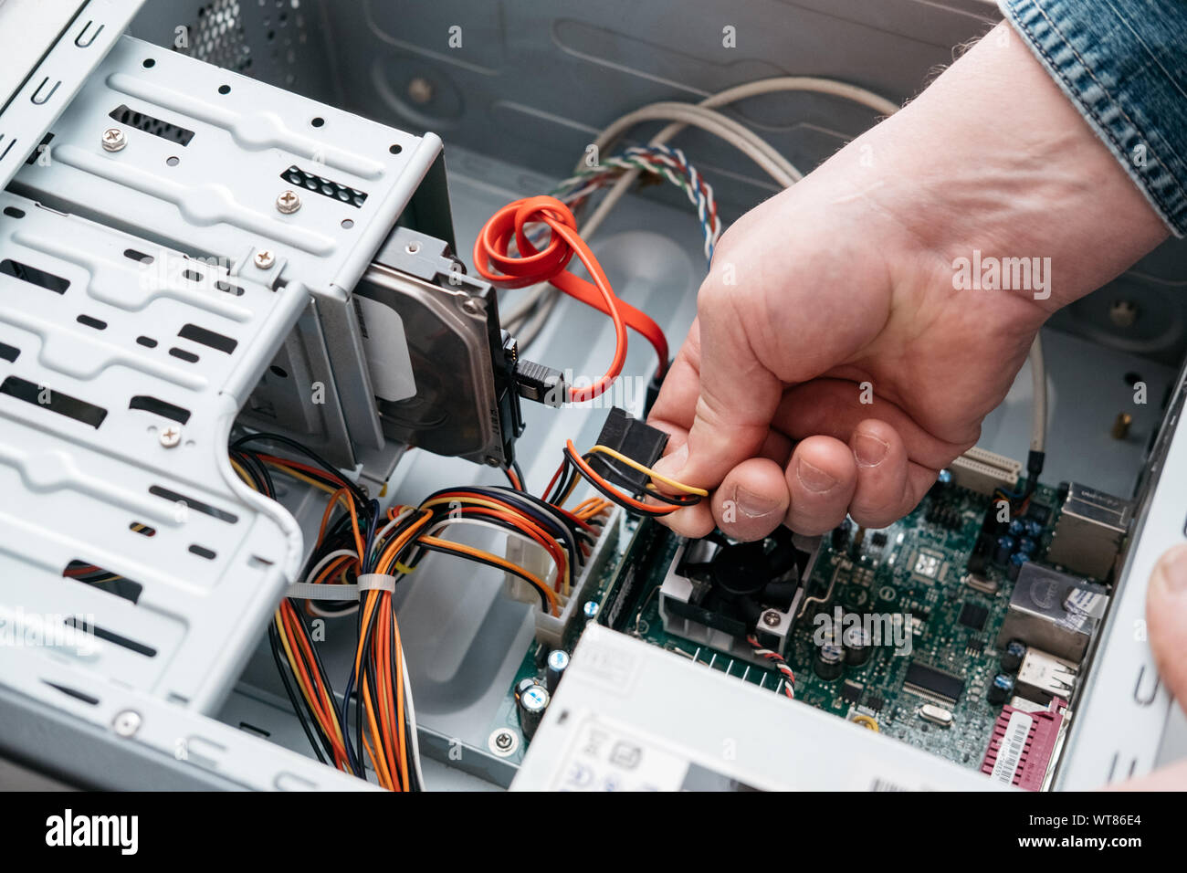 Hand of man plugging SATA (Serial AT Attachment, Serial ATA) data cable ...