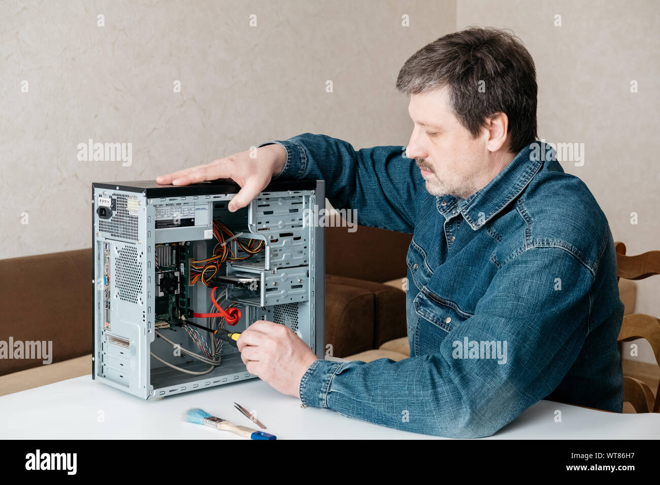 Computer technician engineer with screwdriver in his hand is repairing ...