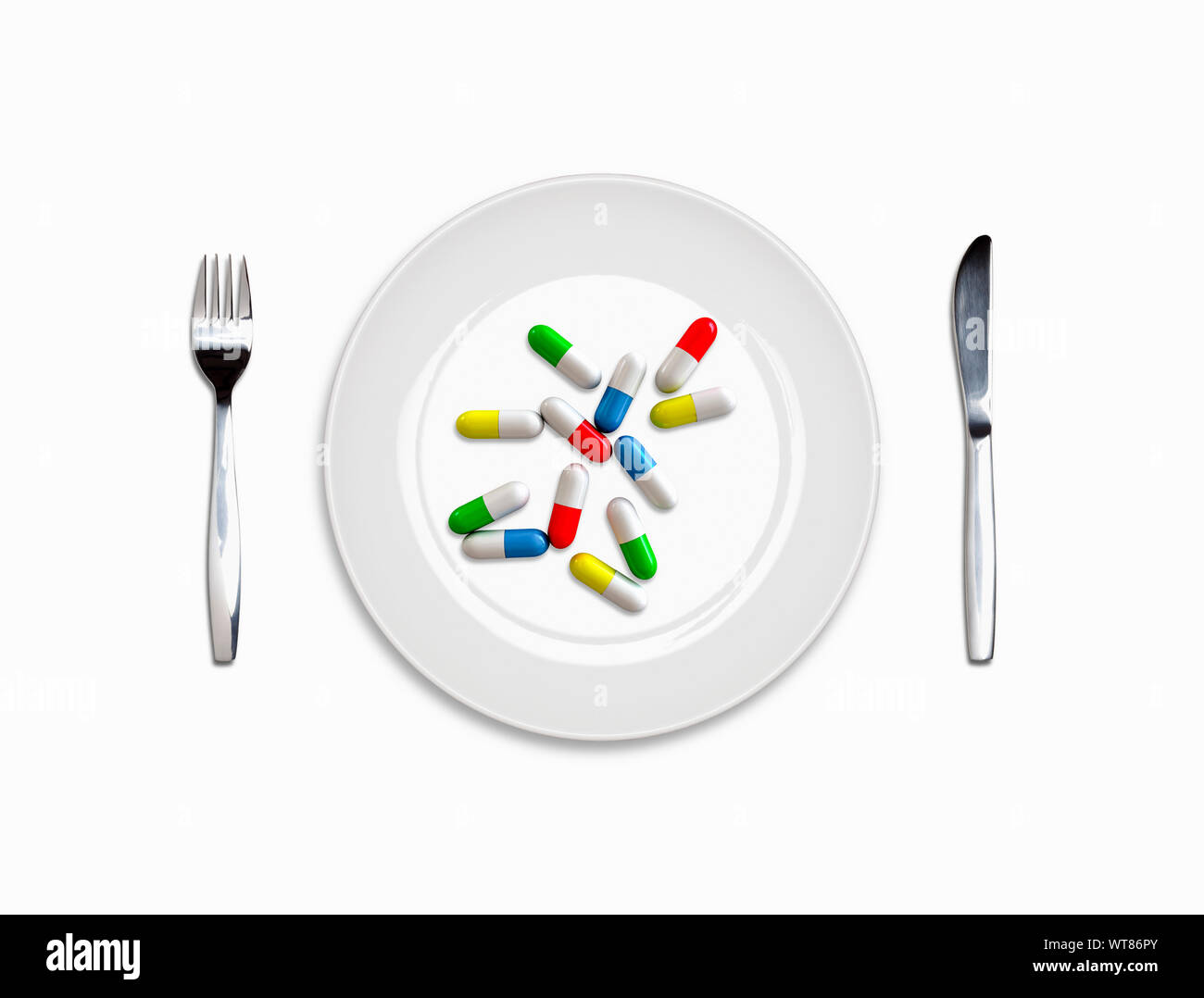 Place setting, white plate, knife and fork with a meal of pill capsules, medicine addiction Stock Photo