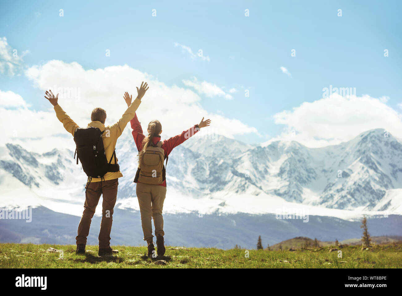 Two successful hikers stands against white mountains with raised hands Stock Photo