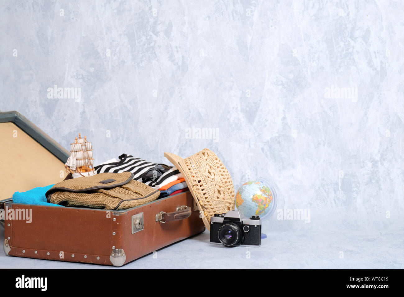 Full travel suitcase on grey background, opened case with travel clothing, accessories. Banner mockup with copy space. Travel or tourism, vacation, ho Stock Photo