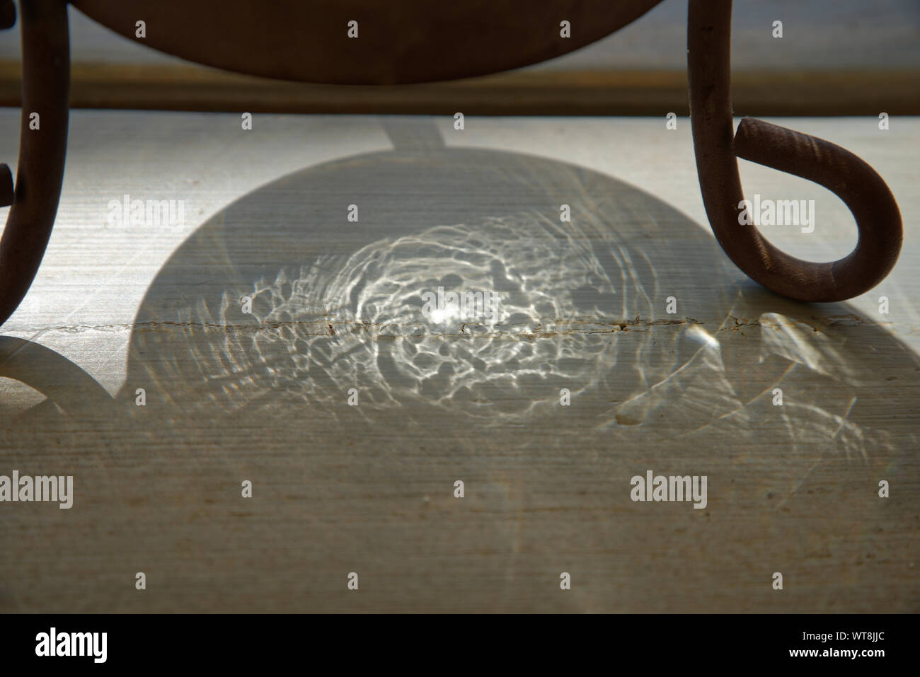 Daylight through crystal glass candleholder produces this light pattern on a table surface. Stock Photo