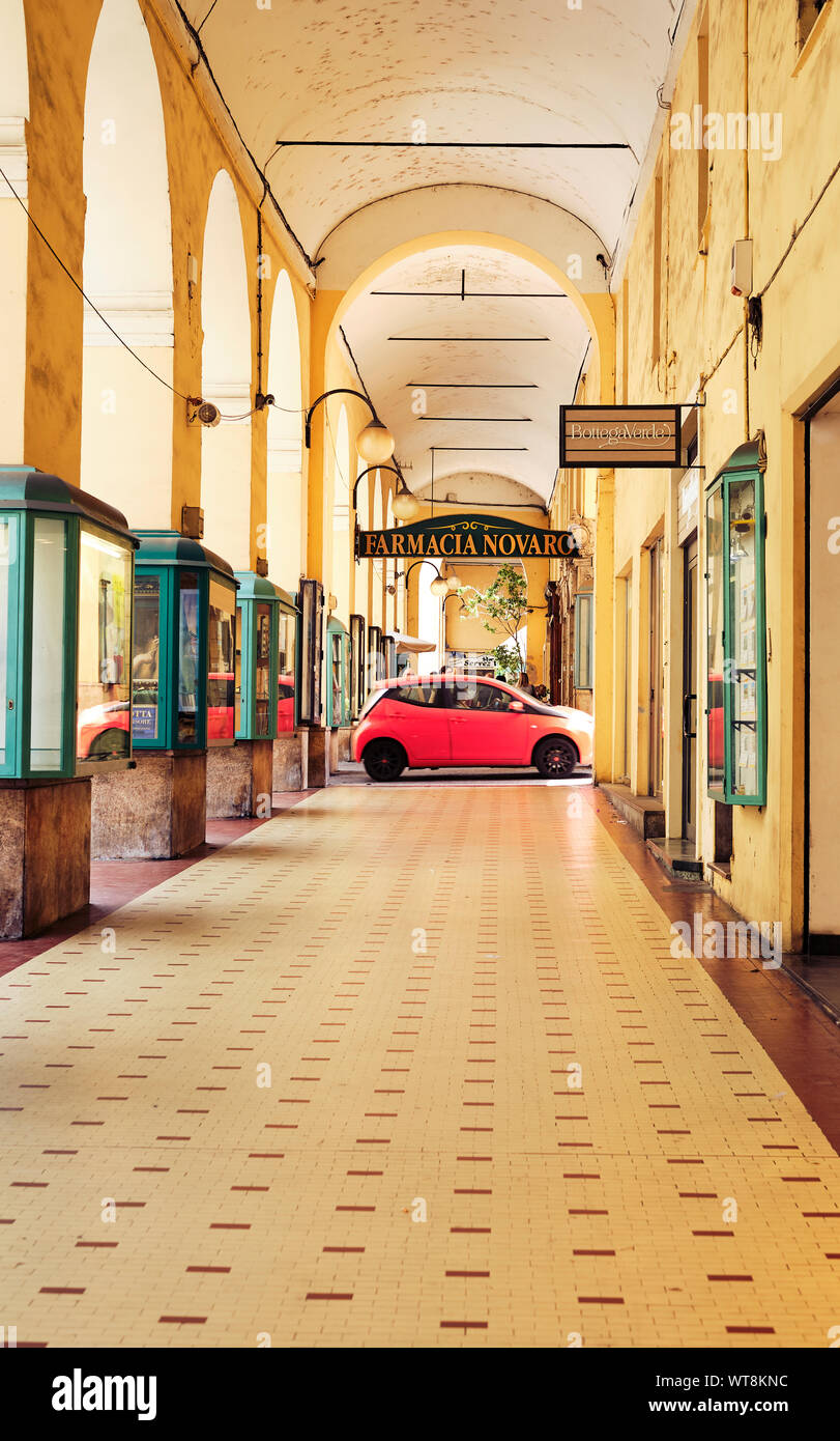 The yellow covered walkway shopping mall with shops and cafes in the coastal town of Oneglia / Imperia on the Italian Riviera in Liguria, Italy. Stock Photo