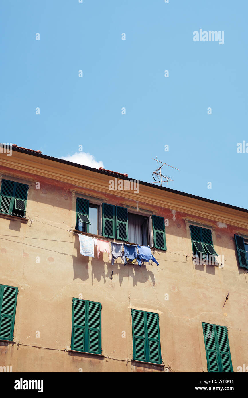 Washing line with clothes drying on a sunny day with blue sky outside an apartment window in Italy. Stock Photo