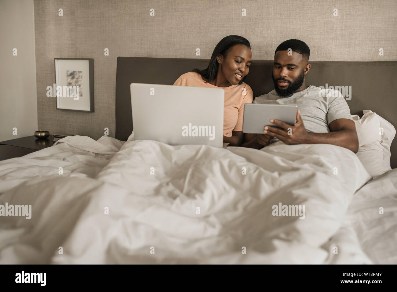 African American couple lying in bed checking their social media Stock ...