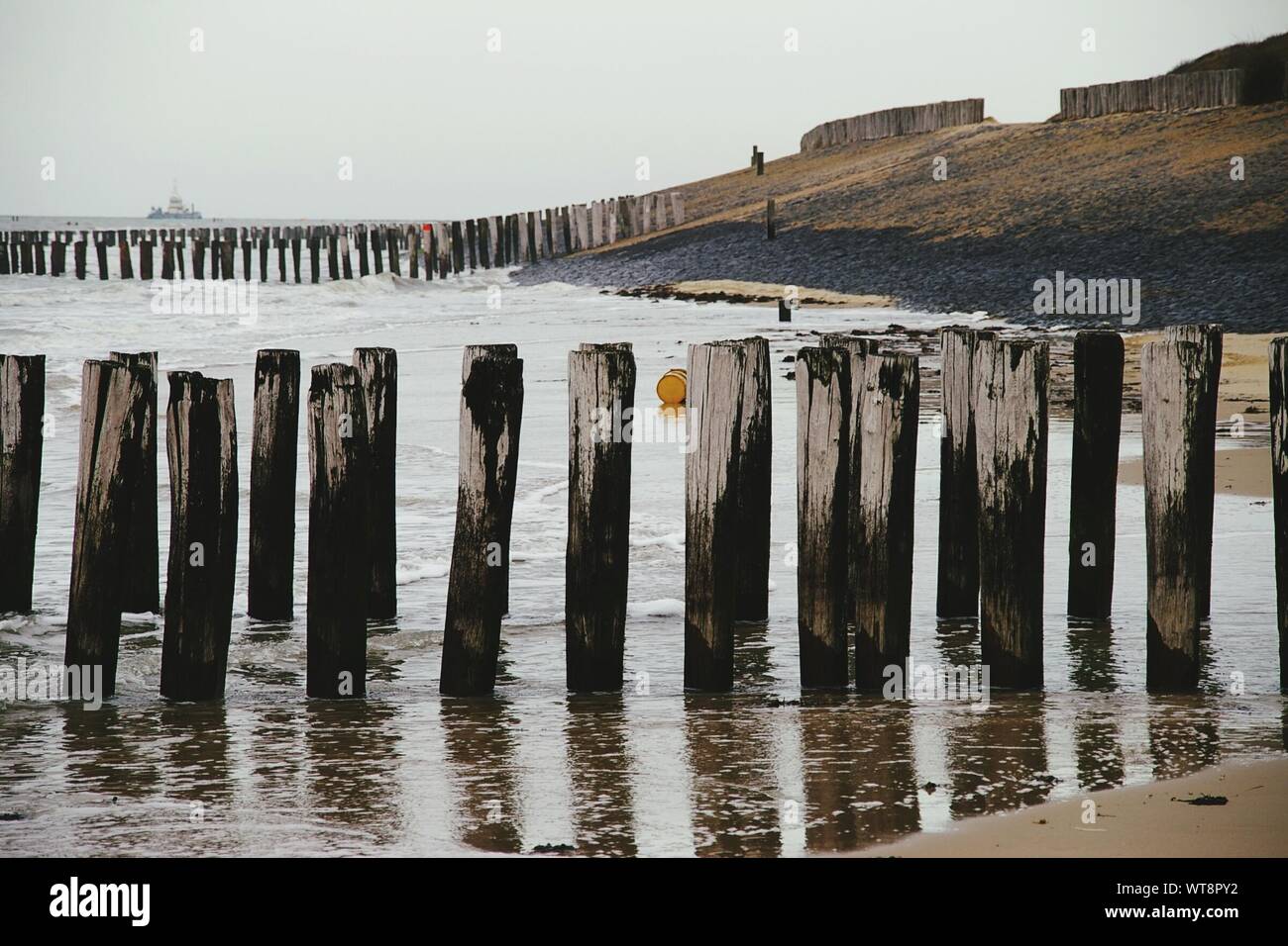 Wooden Groynes On Shore At Sea Against Sky Stock Photo