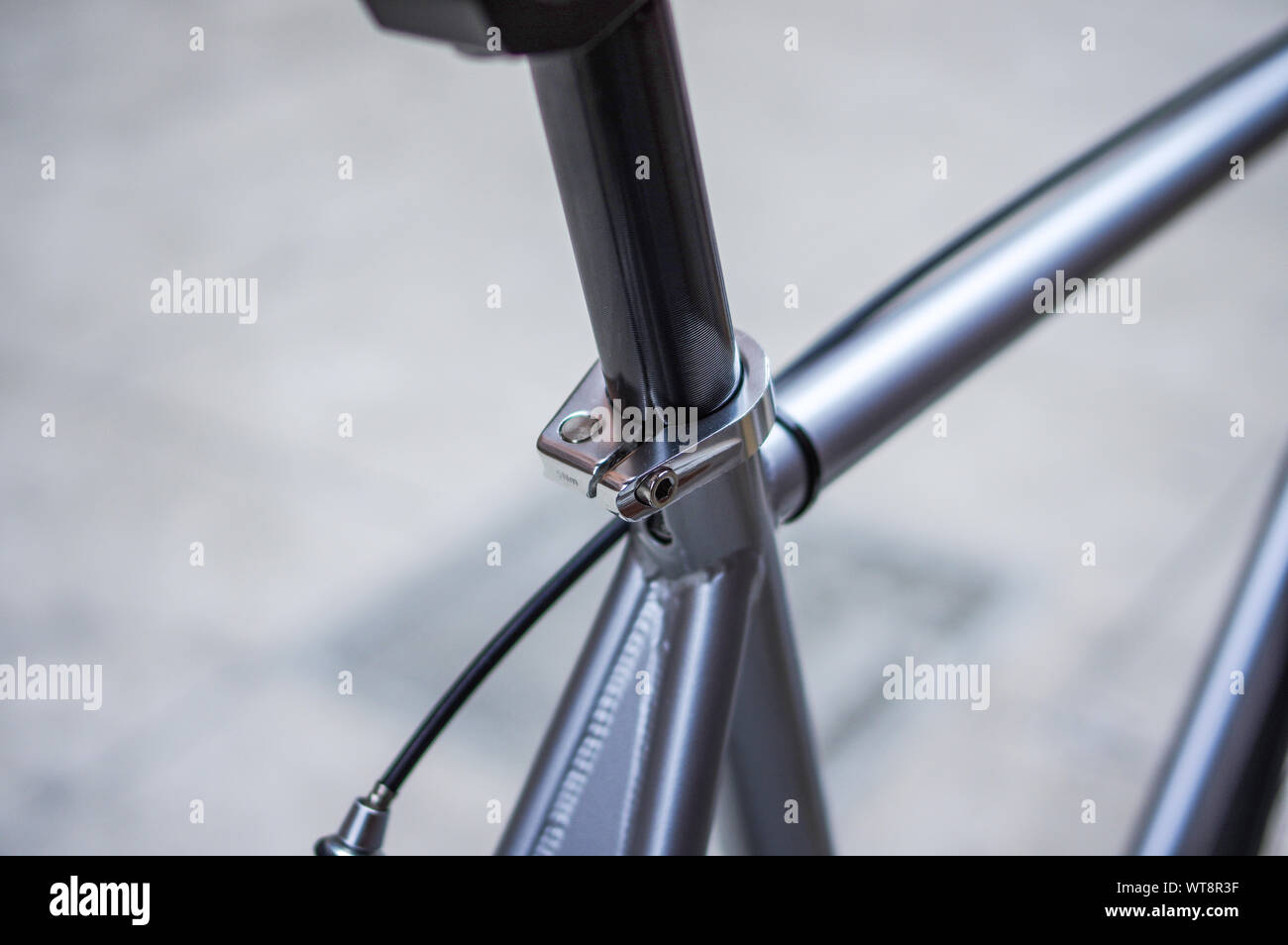 Silver fixed gear bike with black brake cable. Black seat tube and
