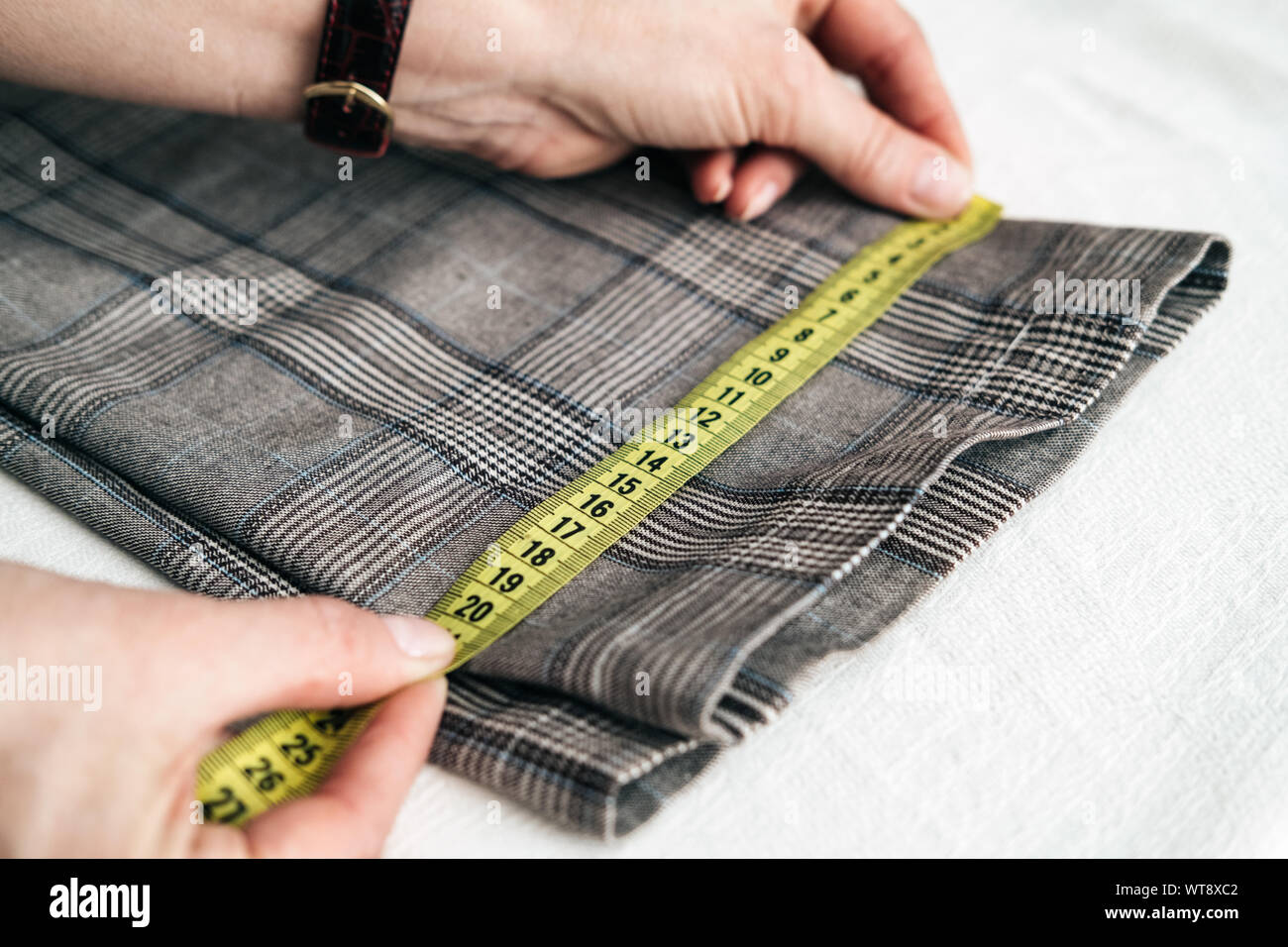 tailor using a measure tape to measure width of pants Stock Photo Alamy
