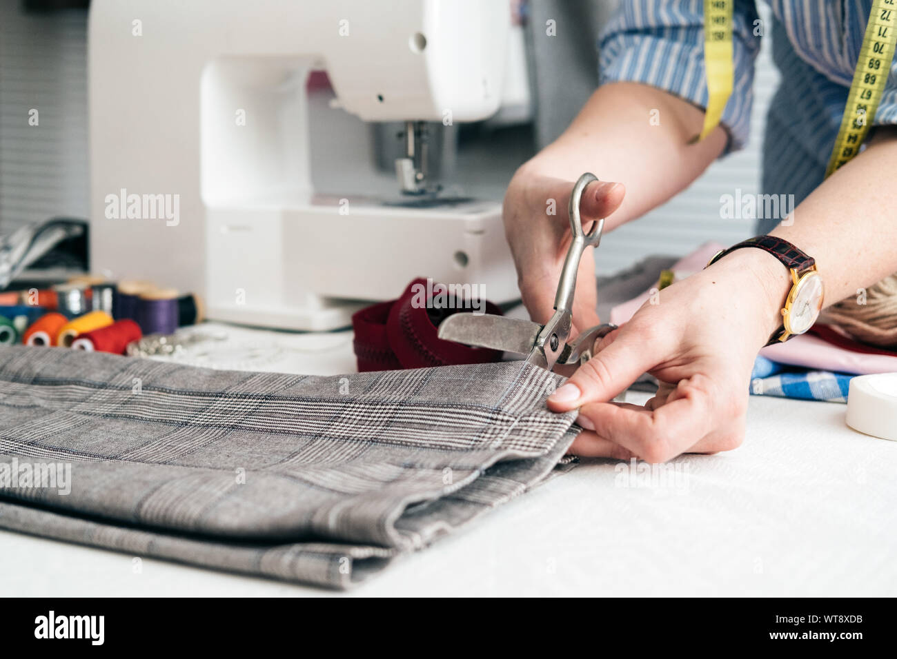 Tailor cutting jeans with scissors at Stock Photo Alamy