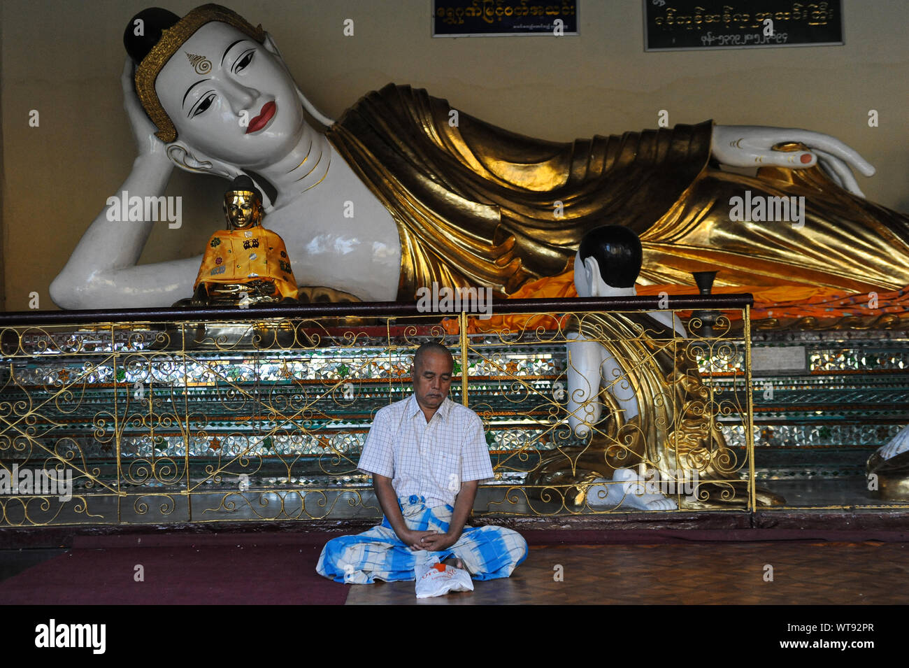 21.01.2014, Yangon, Myanmar, Asia - A man meditates in front of a Buddha statue in the temple compound of the Shwedagon Pagoda. Stock Photo