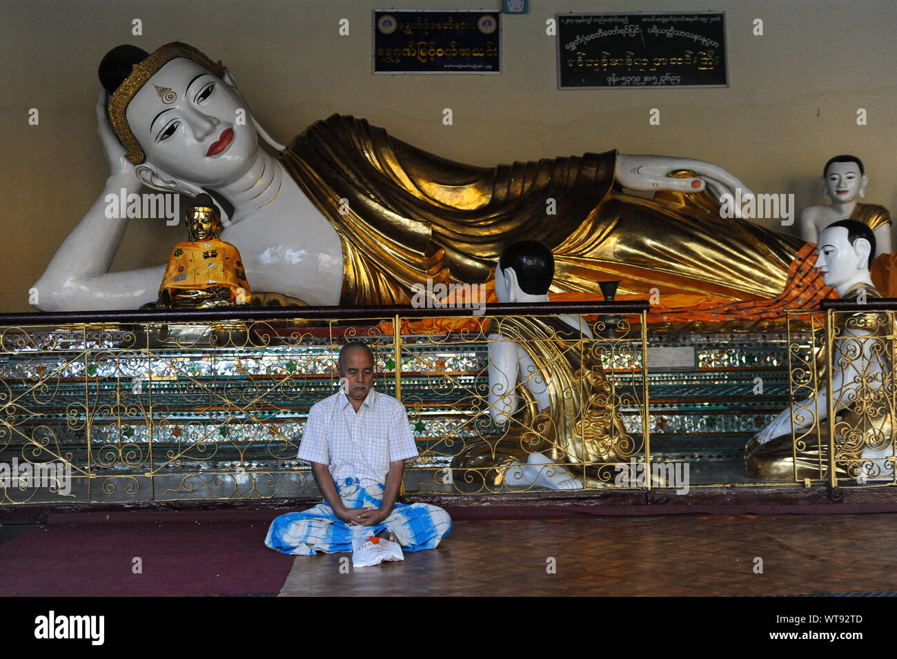21.01.2014, Yangon, Myanmar, Asia - A man meditates in front of a Buddha statue in the temple compound of the Shwedagon Pagoda. Stock Photo