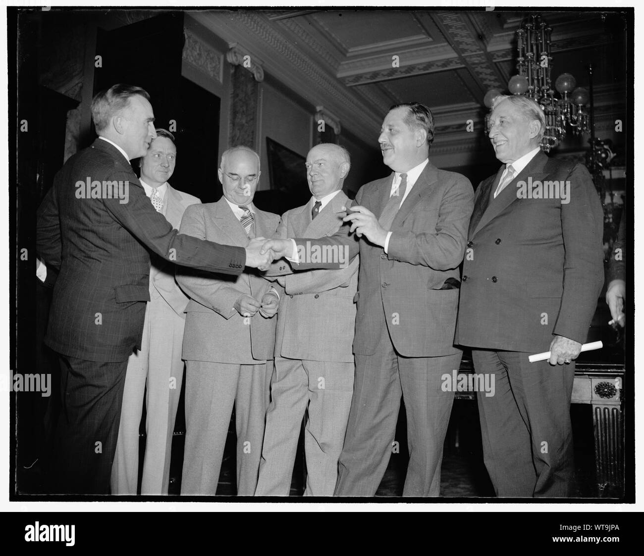 Members congratulate chairman of congressional monopoly committee. Washington, D.C., July 1. Senator Joseph C. O'Mahoney (left) of Wyoming, named Chairman of the Congressional Monopoly Committee at their first meeting today, receives the congratulations of other members of the investigating group. O'Mahoney is the author of the resolution for the inquiry. Pictured, left to right: Senator O'Mahoney, William O. Douglas, S.E.C. Chairman; Rep. Edward C. Eicher, Rep. Hatton W. Sumners, Vice Chairman; Assistant Attorney General Thurman Arnold, and Senator William H. King, 7/1/38 Stock Photo